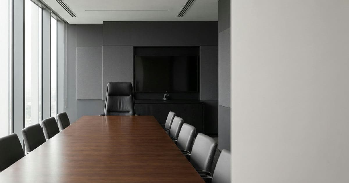 Empty executive boardroom with chair at head of table, professional office setting.