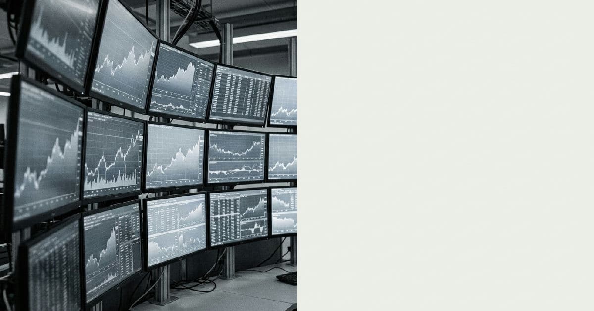 Trading floor monitors displaying upward trending market data visualizations in desaturated tones.