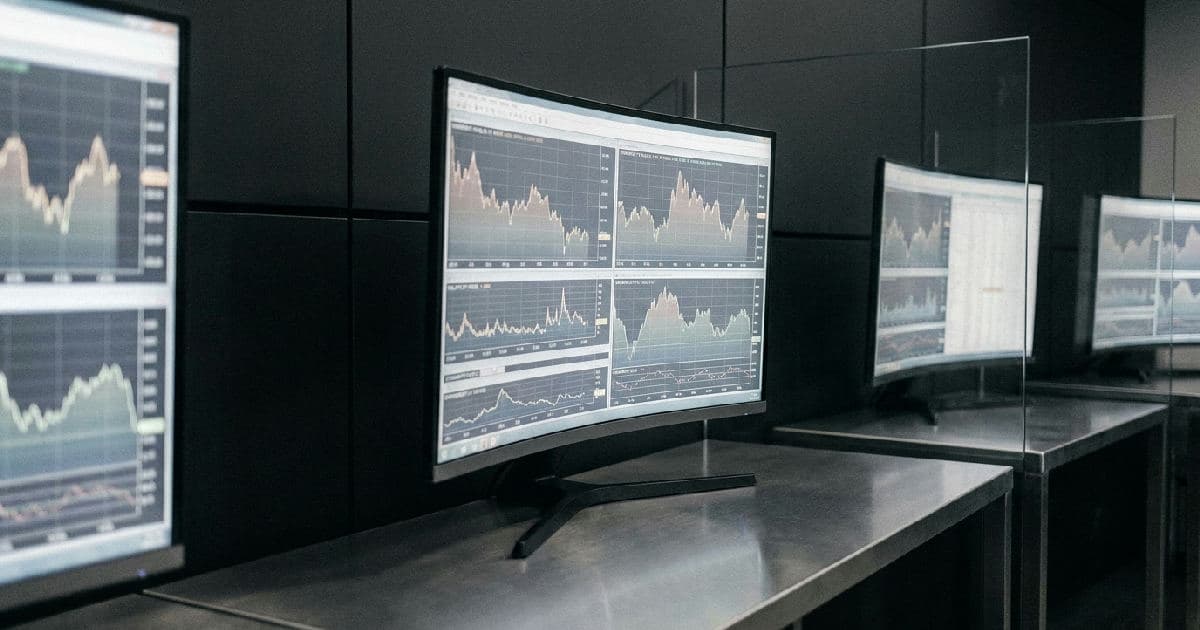 Market data screens displaying commodity price charts and trading information in a desaturated colour scheme.