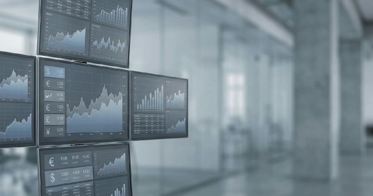 Multiple screens showing economic charts and financial data in muted tones.