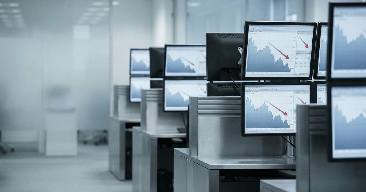 Multiple financial data screens showing declining market charts in a trading environment.