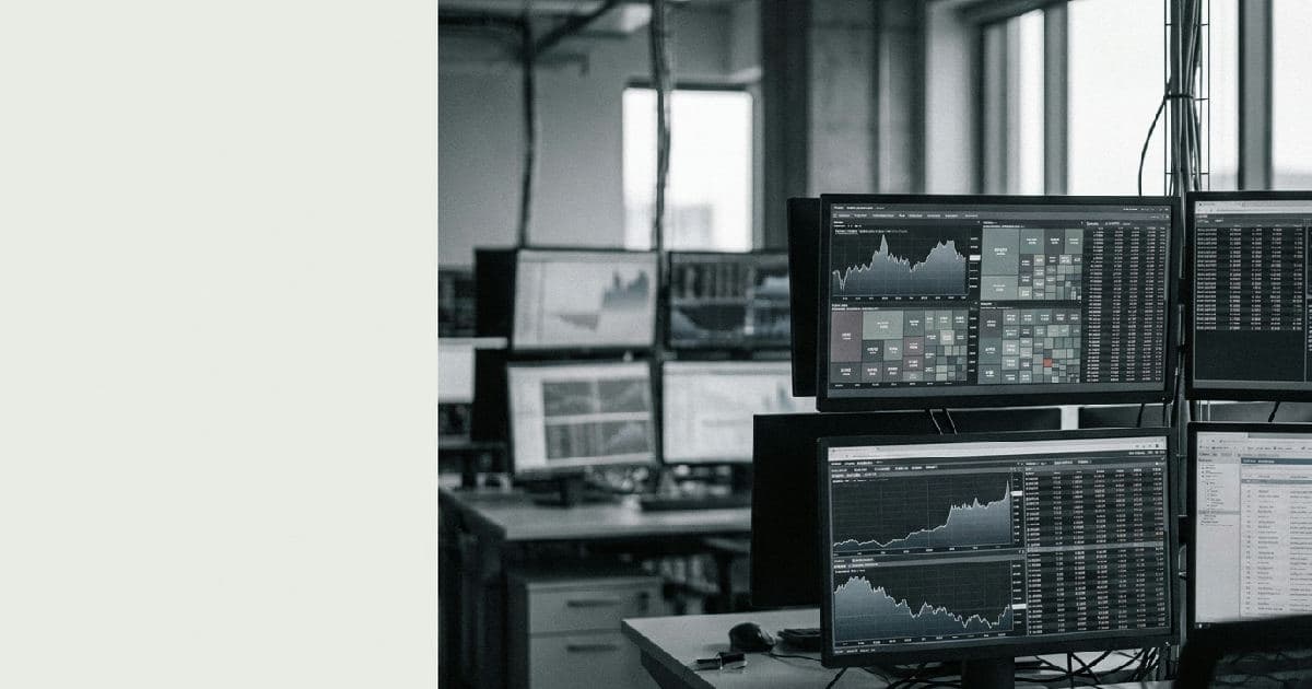 Trading floor monitors displaying abstract market data visualisations in muted tones, no people visible.