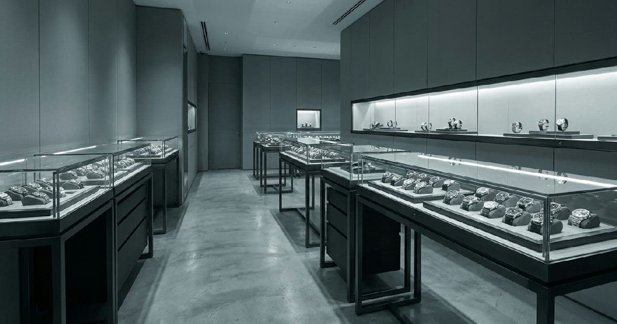 Luxury watch retail display cases with polished surfaces and soft lighting in desaturated tones.