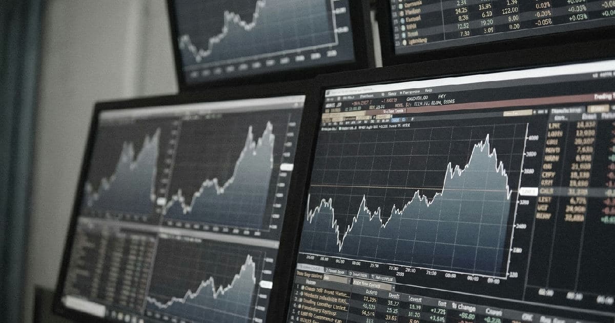 Multiple financial market data screens displaying charts and metrics in muted tones.