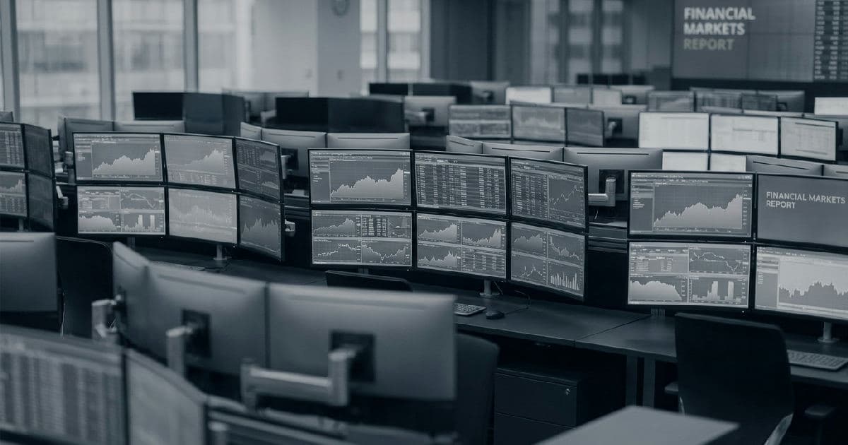 Computer monitors displaying financial data and market charts in a trading environment.