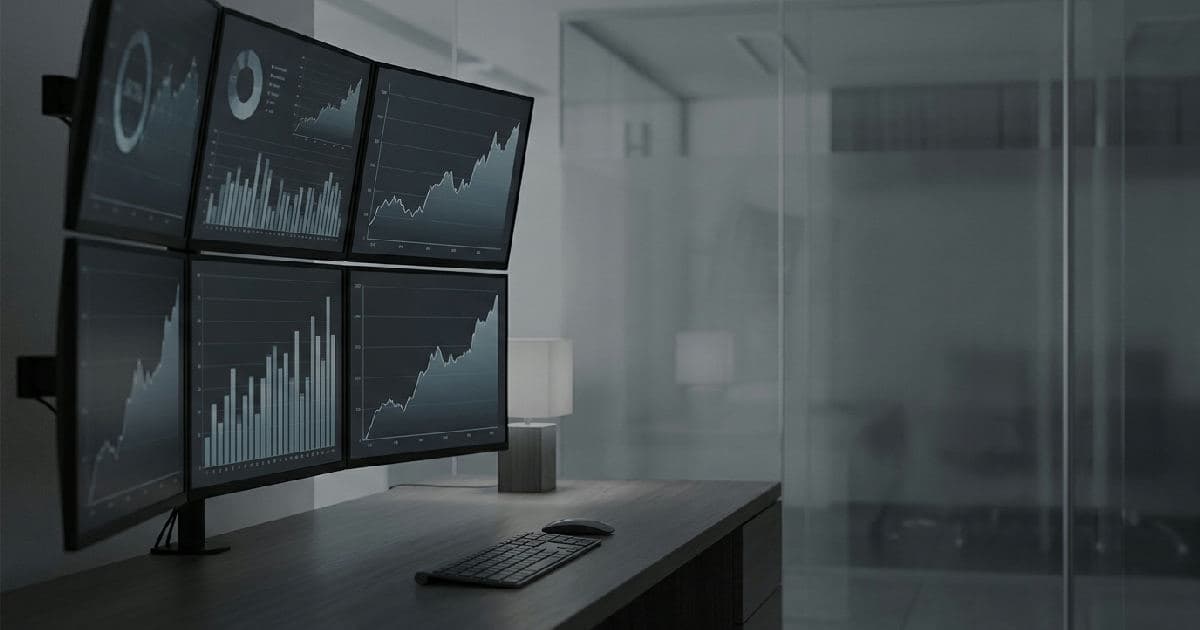 Abstract financial data visualisation on multiple monitors showing upward trend lines in muted tones.