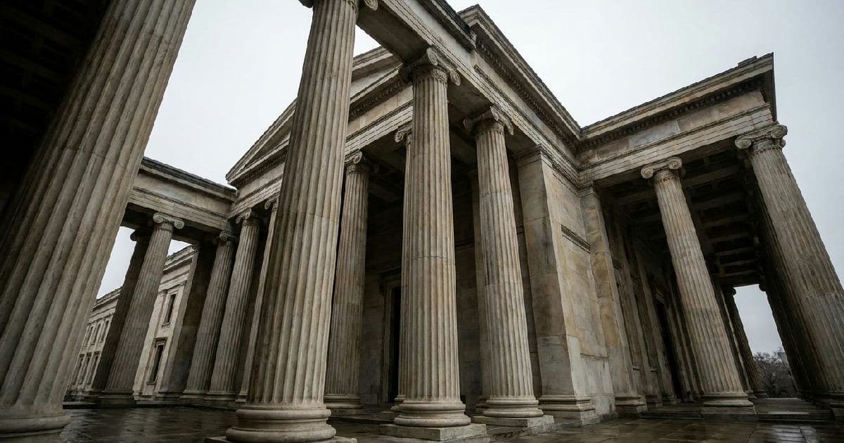 Classical marble columns of a government building exterior beneath an overcast sky.
