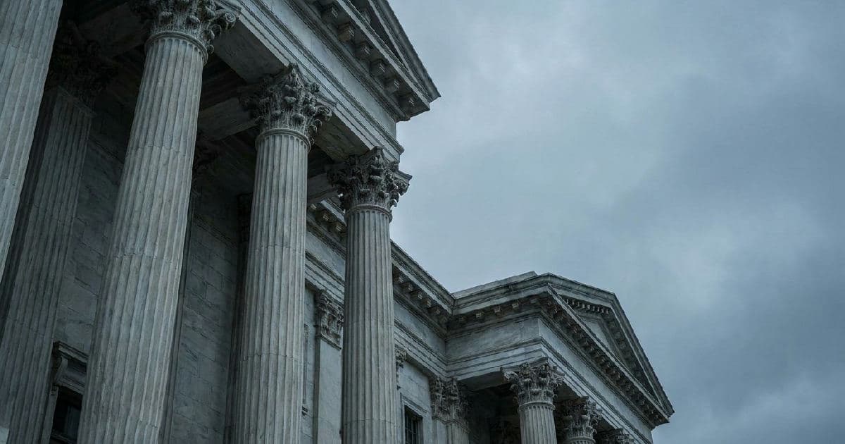 Classical marble columns of a government building under overcast sky, architectural composition emphasising institutional scale.
