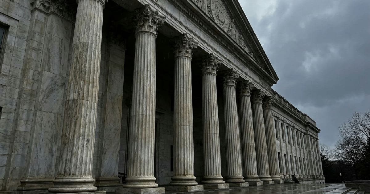 Marble columns of a government building beneath an overcast sky, classical architecture.