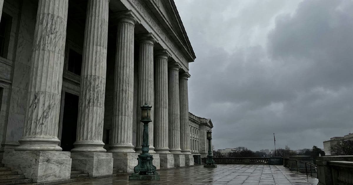 Marble columns of a government building under overcast sky, classical architectural detail.