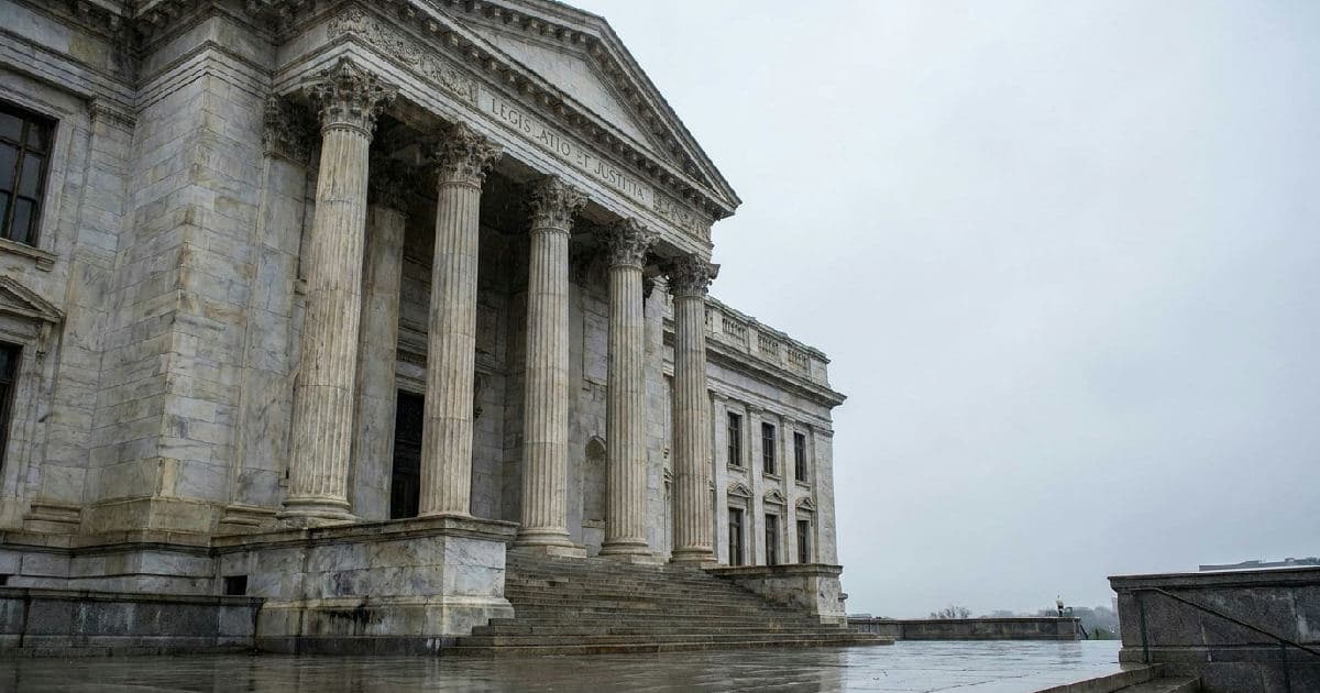 Classical marble columns of government building exterior under overcast sky.