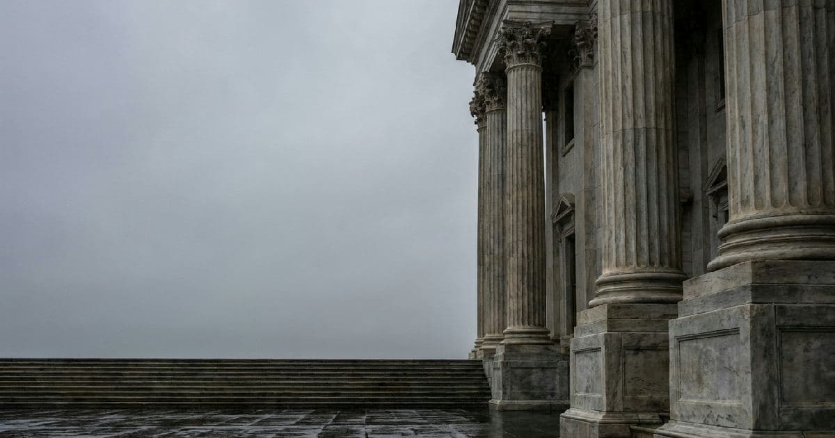Classical marble columns of a government building under overcast sky, architectural detail shot.