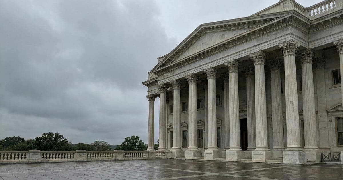 Classical marble columns of a government building under overcast sky, no people visible.