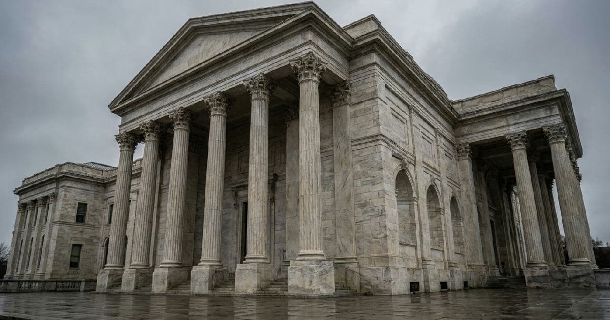 Classical marble columns and government building exterior under overcast sky, no people.