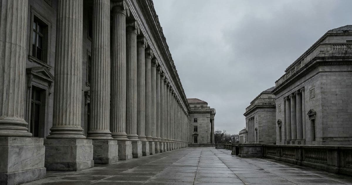 Classical marble columns of a government building under overcast sky, no people present.