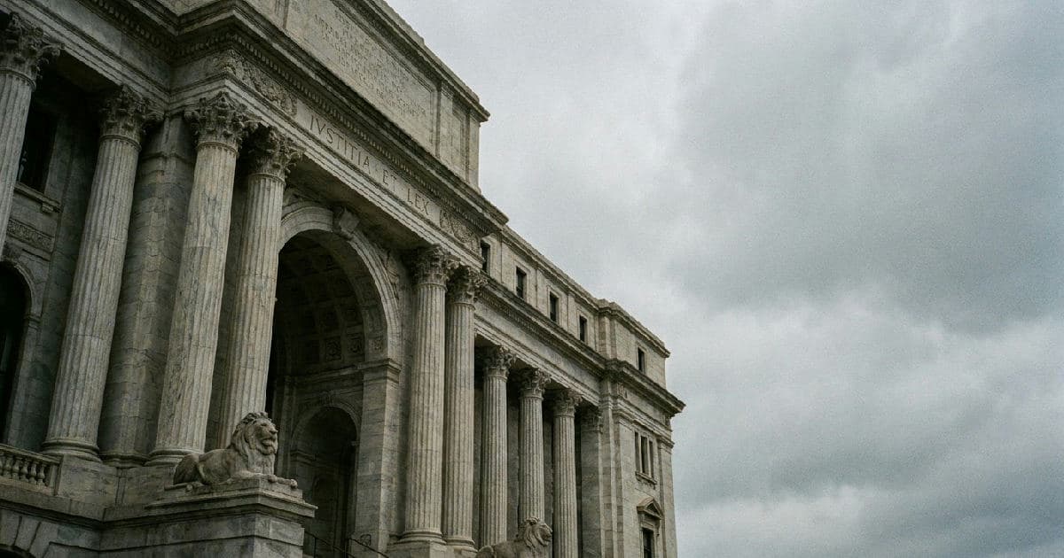 Classical marble columns of a government building exterior beneath overcast sky.