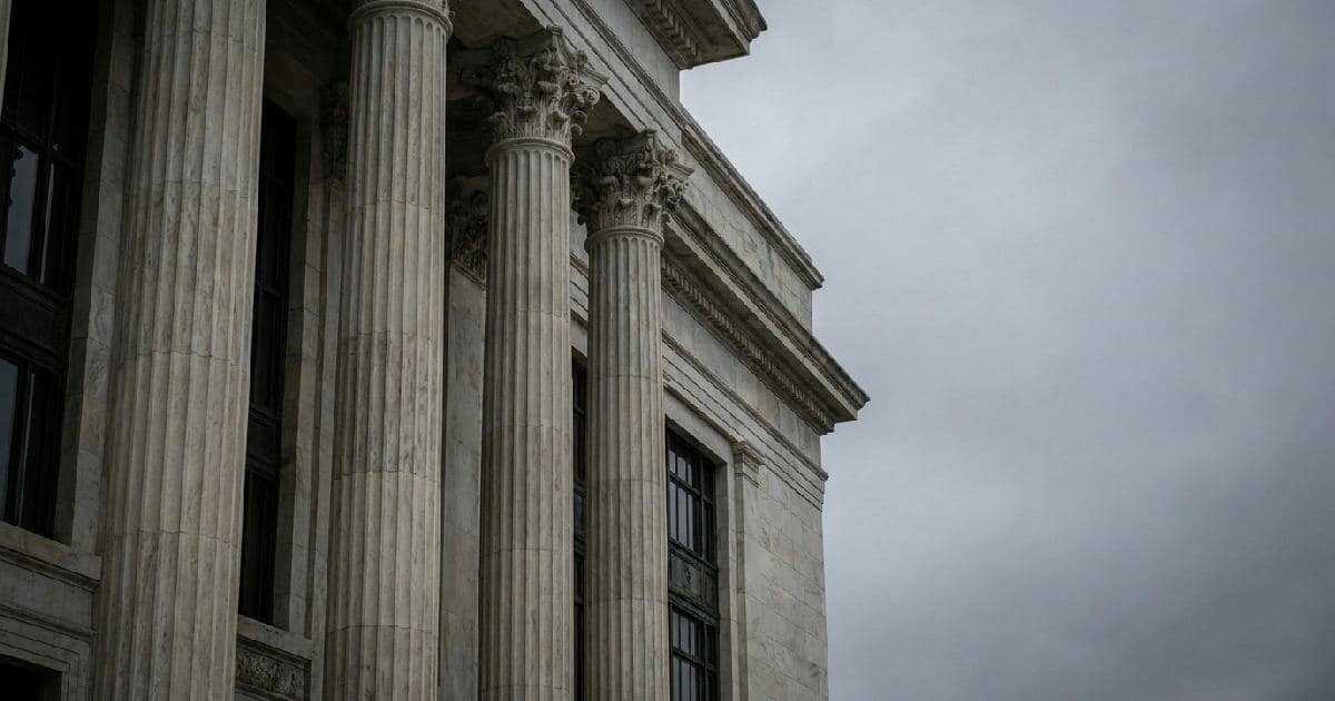 Classical marble columns of a government building under overcast sky, no people present.