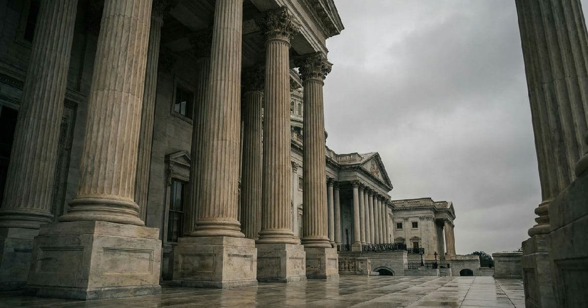 Classical government building with marble columns beneath overcast sky, empty plaza foreground.