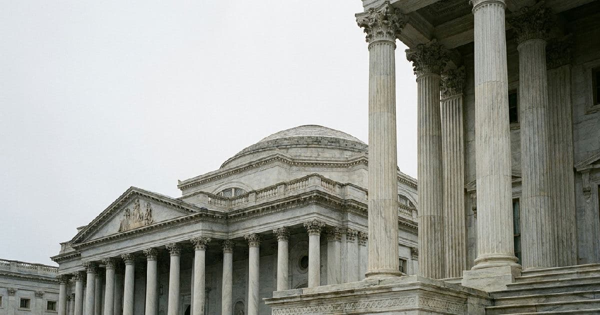 Classical marble columns of a government building under overcast sky, symbolising regulatory authority.
