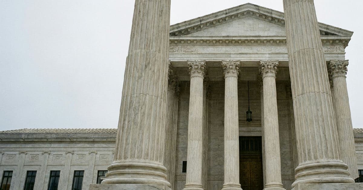 Classical marble columns of a government building under overcast sky, empty and formal.