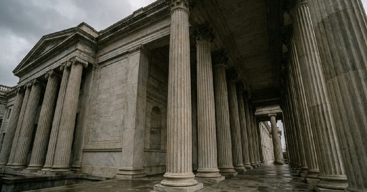 Classical marble columns of a government building under overcast sky, no people present.