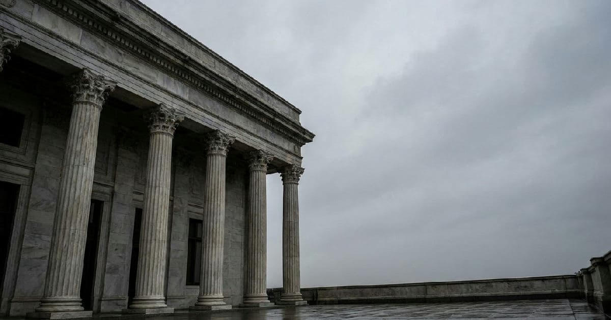Classical marble columns of a government building beneath overcast sky, architectural authority.