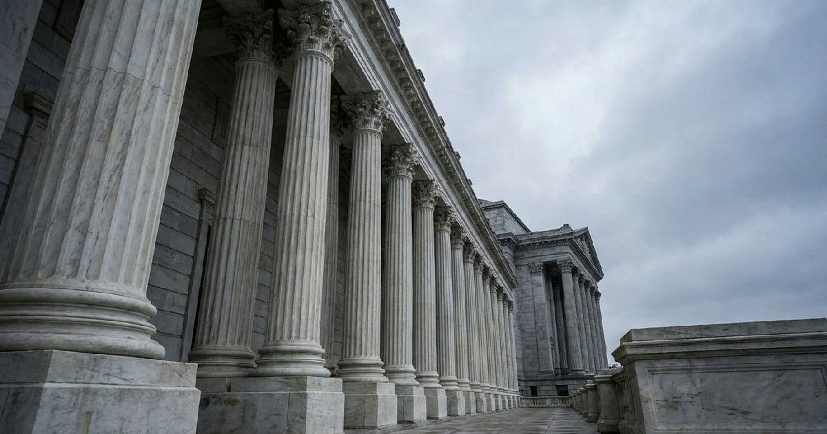 Classical marble columns of a government building facade beneath an overcast sky.