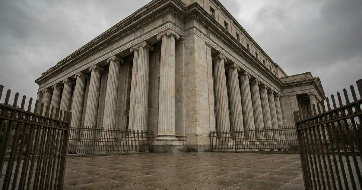 Classical marble columns of a government building beneath an overcast sky, institutional and formal.