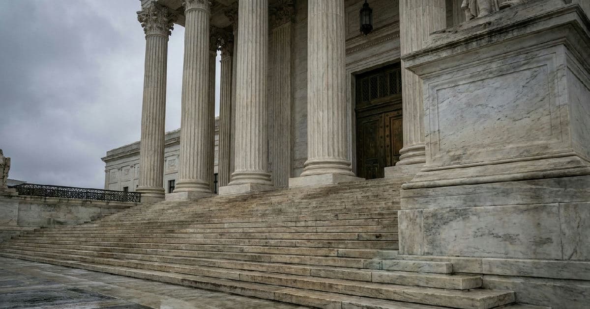Classical marble columns and stone steps of a government building exterior under overcast sky.