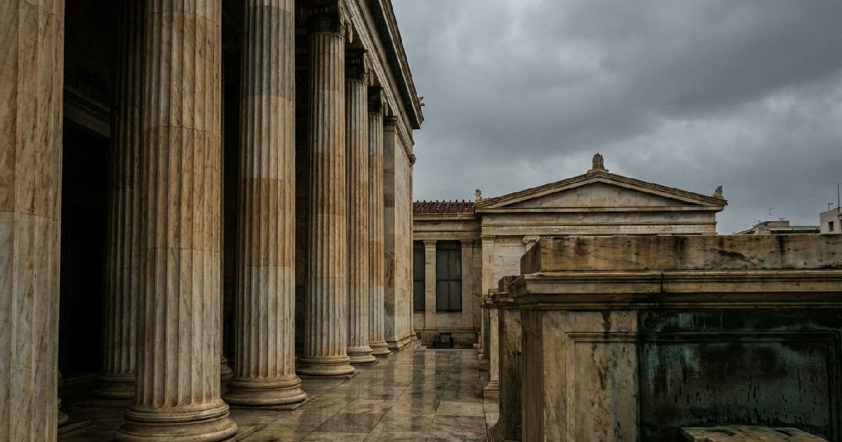 Classical marble columns of a government building beneath an overcast sky, symbolizing institutional independence and legal authority.
