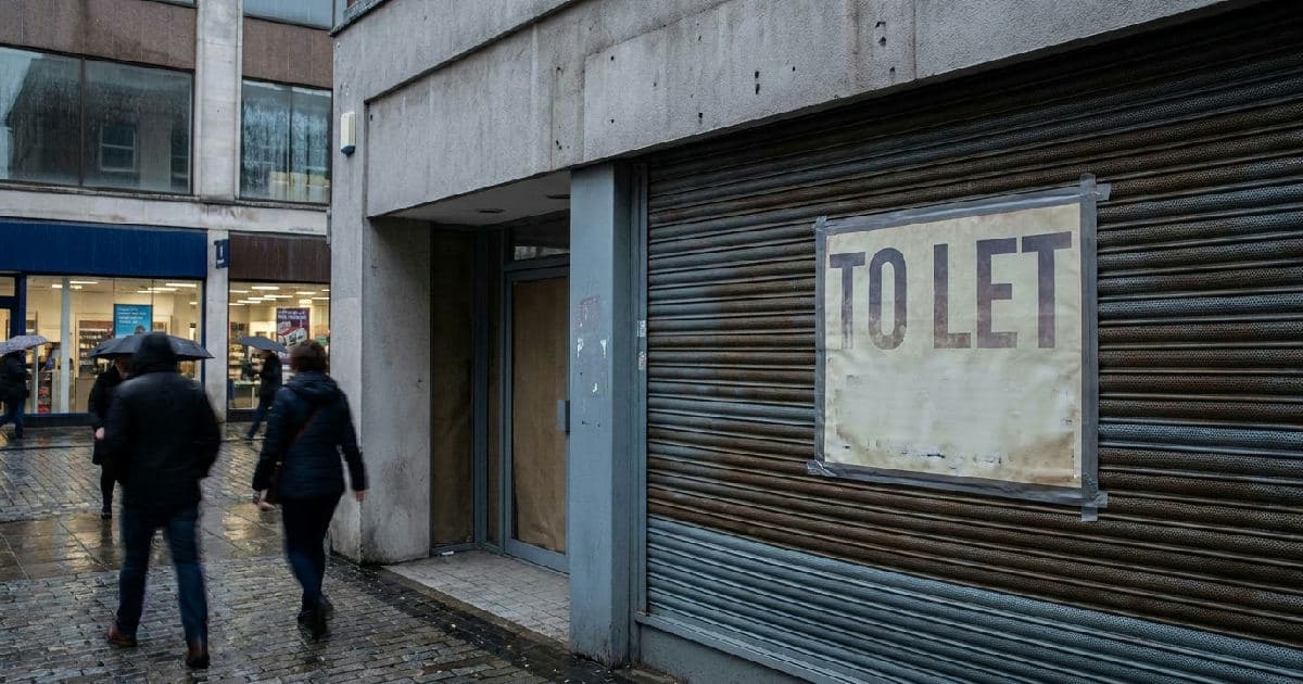 Empty retail storefront with shuttered windows on a high street, neutral tones, natural light.